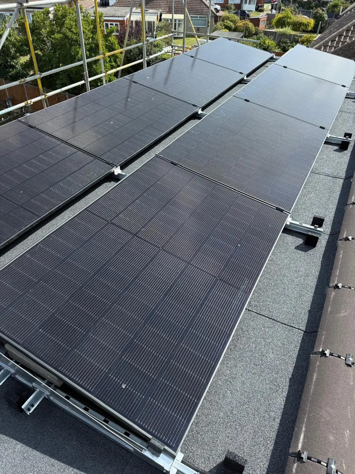 All black solar panels laid in rows across the same felt flat roof once the array was complete.
