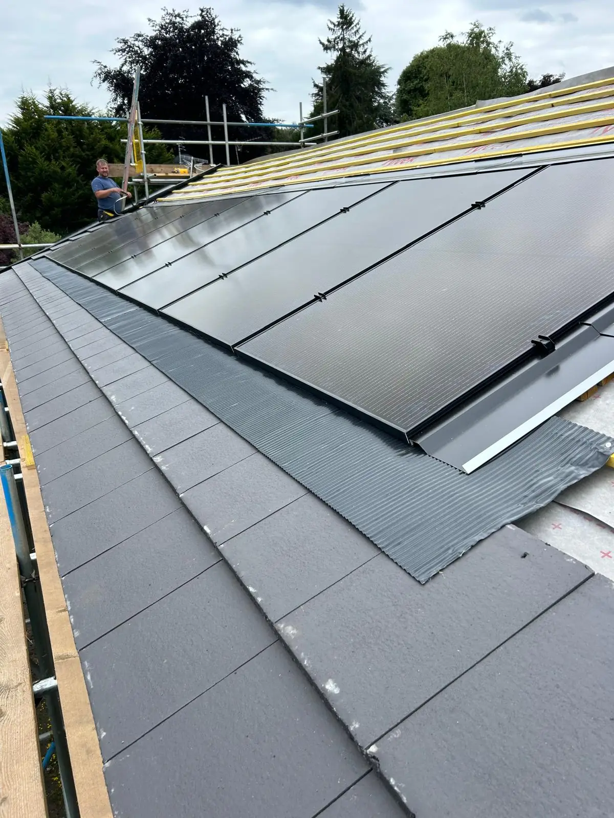 Close view along the tile roof showing the flashing detail where the in roof array meets the surrounding tiles.