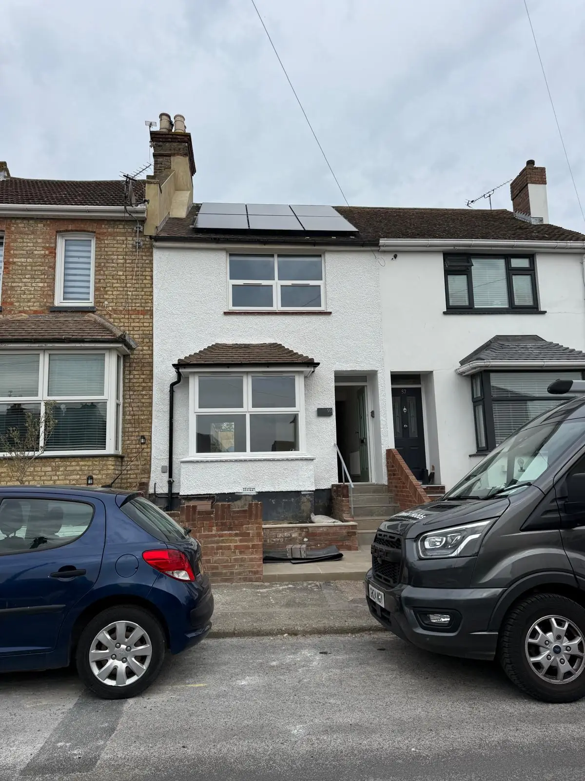 The company van parked outside a mid terrace house with a solar array on the front roof slope.